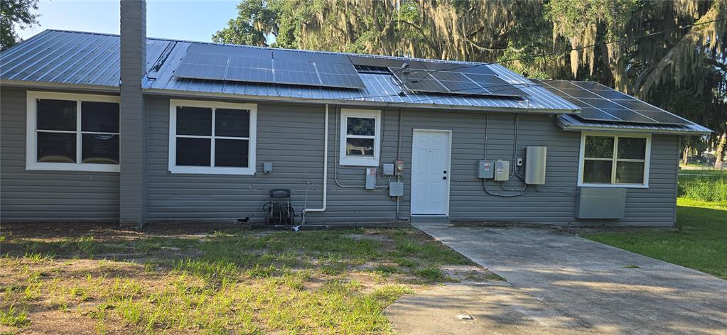 A gray house with a metal roof, solar panels, and a concrete driveway — 318 CHESNEY BLVD, FROSTPROOF, FL