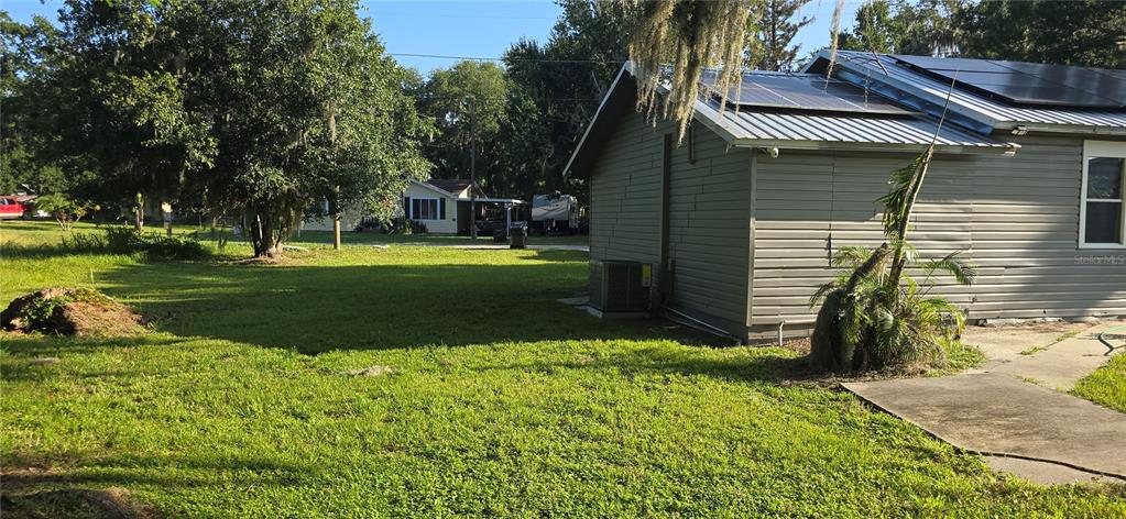 A side view of a house with solar panels and a large grassy yard — 318 CHESNEY BLVD, FROSTPROOF, FL