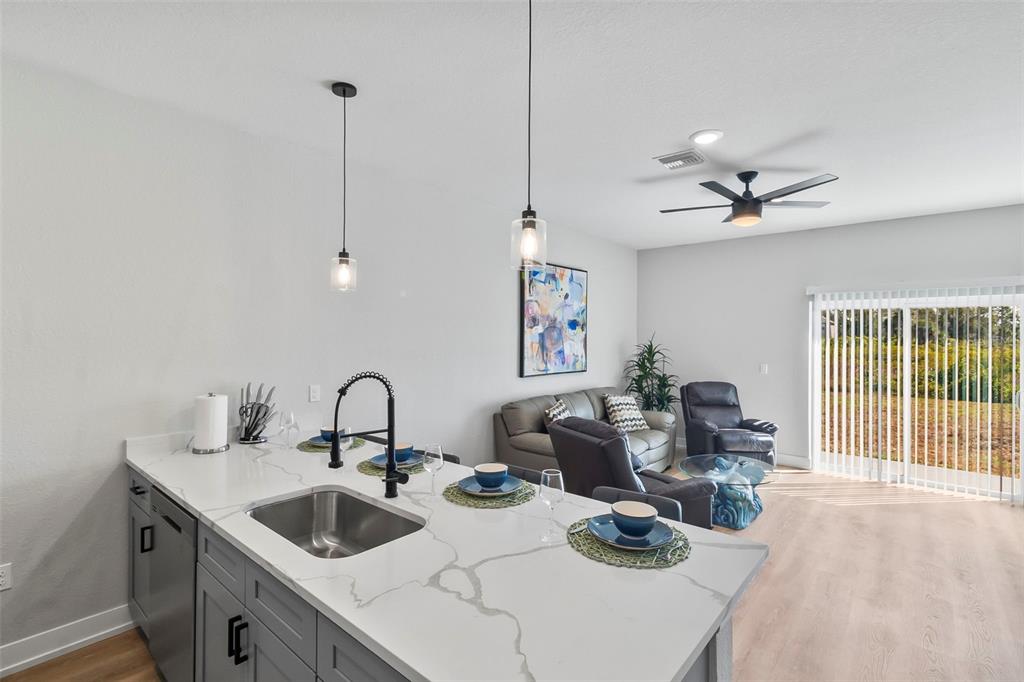 A kitchen island with a sink and pendant lights overlooks a living room with seating — 9155 AGATE STREET, PORT CHARLOTTE, FL