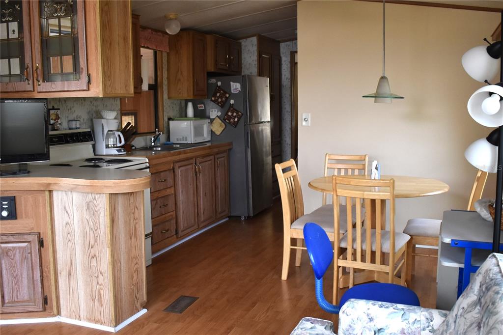 A kitchen with wood cabinets and a dining area with a round table and chairs — 9000 US HWY 192 UNIT 489, CLERMONT, FL