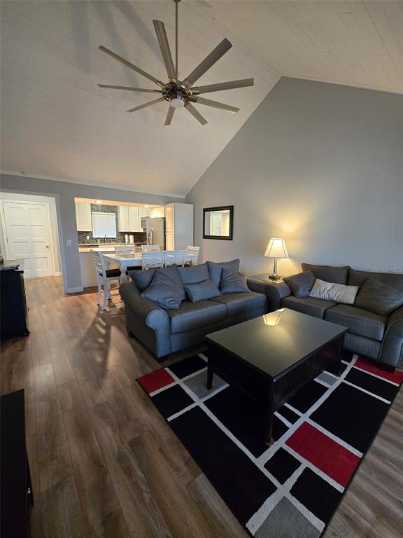 A living room with a vaulted ceiling, ceiling fan, and an adjacent dining area — 1118 VILLA LANE UNIT S, APOPKA, FL