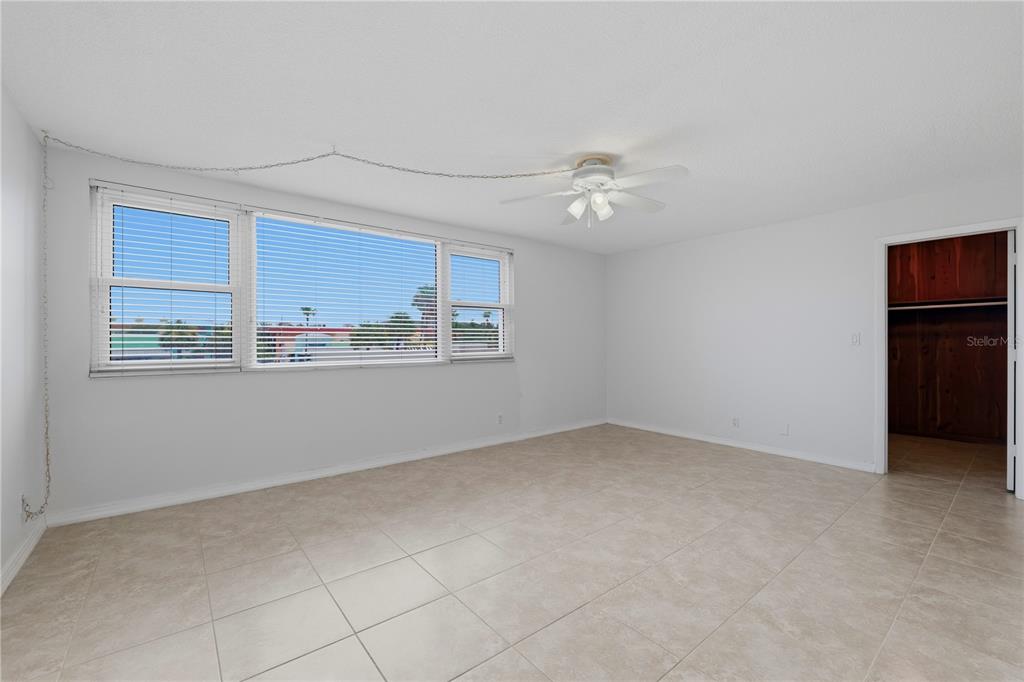 A bright, empty room with white walls, tile floors, a ceiling fan, and large windows — 675 S GULFVIEW BOULEVARD UNIT 206, CLEARWATER BEACH, FL