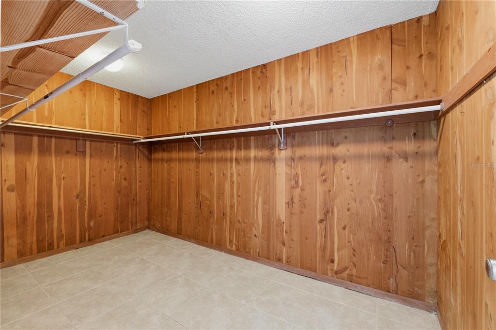 A walk-in closet features wood-paneled walls, tile flooring, and white wire shelving — 675 S GULFVIEW BOULEVARD UNIT 206, CLEARWATER BEACH, FL
