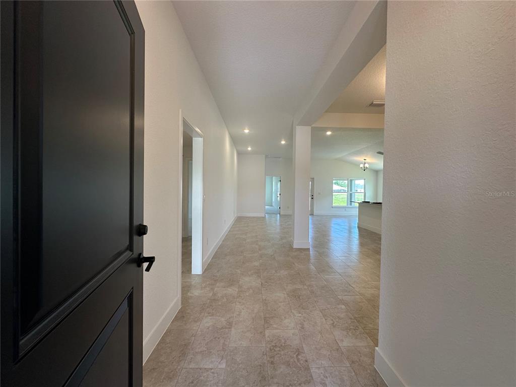 A view from an open doorway into a tiled hallway leading to an open living area — 12551 NE 48TH TERRACE, OXFORD, FL