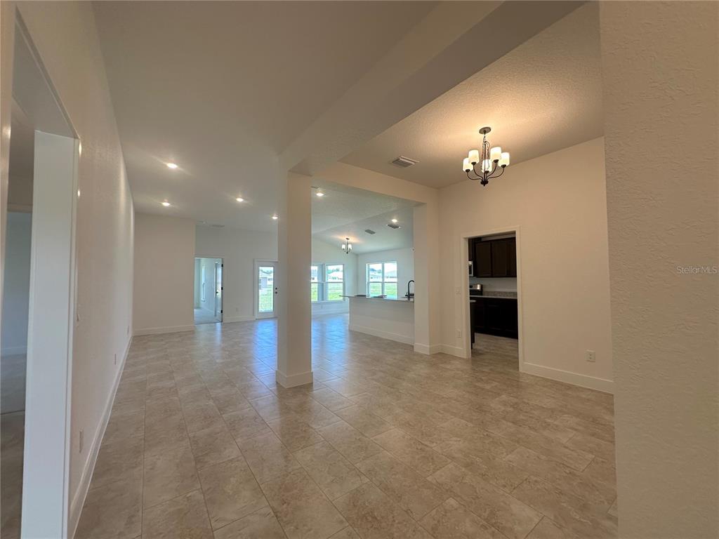 An open-concept interior features tile flooring, a chandelier, and a view into the kitchen — 12551 NE 48TH TERRACE, OXFORD, FL