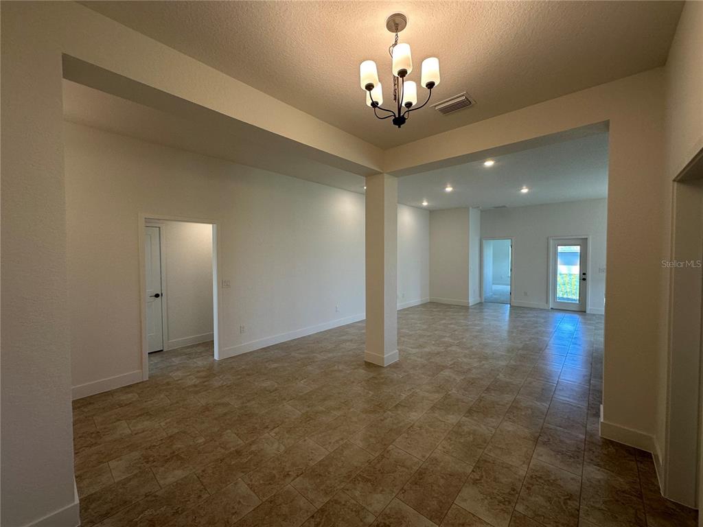 An open-concept living area features tile flooring, a central support column, and a chandelier — 12551 NE 48TH TERRACE, OXFORD, FL