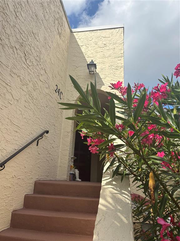 Exterior view of a stucco building entrance with stairs, a wall-mounted lantern, and blooming oleander — 6101 34TH STREET W UNIT 24C, BRADENTON, FL