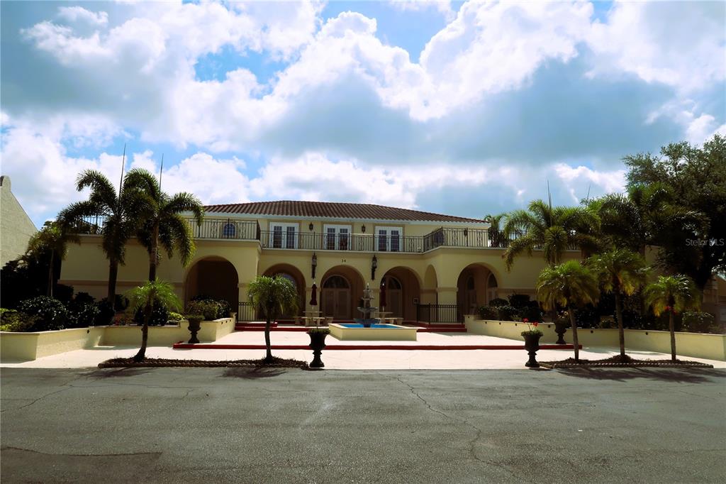 A two-story Mediterranean-style building features arched entryways, a central fountain, and a second-floor balcony — 6101 34TH STREET W UNIT 24C, BRADENTON, FL