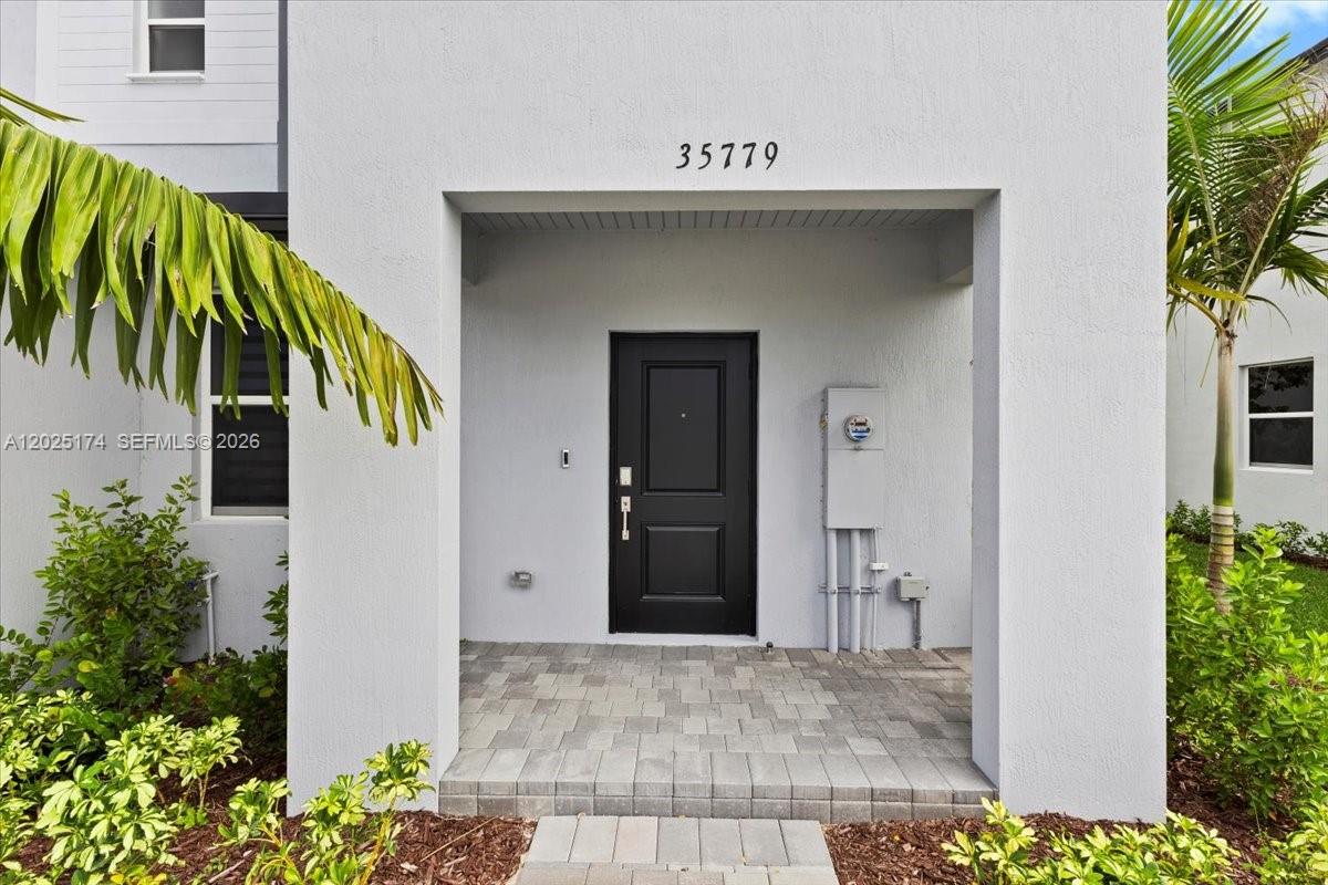 The exterior of a house features a covered entryway with a black door and pavers — 35779 SW 178th Ct, Miami FL 33034, MIAMI, FL