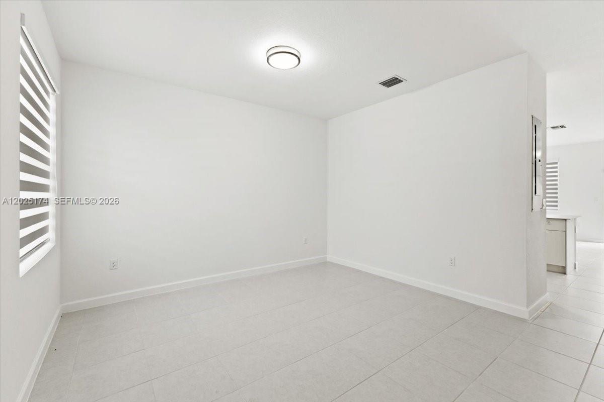 A bright, empty room features white walls, light-colored tile flooring, and a window with blinds — 35779 SW 178th Ct, Miami FL 33034, MIAMI, FL
