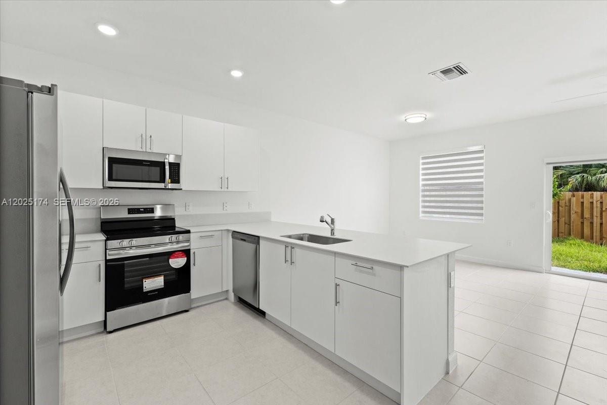 A modern kitchen features white cabinets, stainless steel appliances, and a central island — 35779 SW 178th Ct, Miami FL 33034, MIAMI, FL