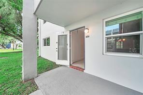 A concrete patio leads to an open doorway and a window on a white building exterior — 7897 Golf Circle Drive # 112, Margate FL 33063, MARGATE, FL