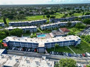 An aerial view shows a multi-story apartment complex with a swimming pool and parking lot — 7897 Golf Circle Drive # 112, Margate FL 33063, MARGATE, FL