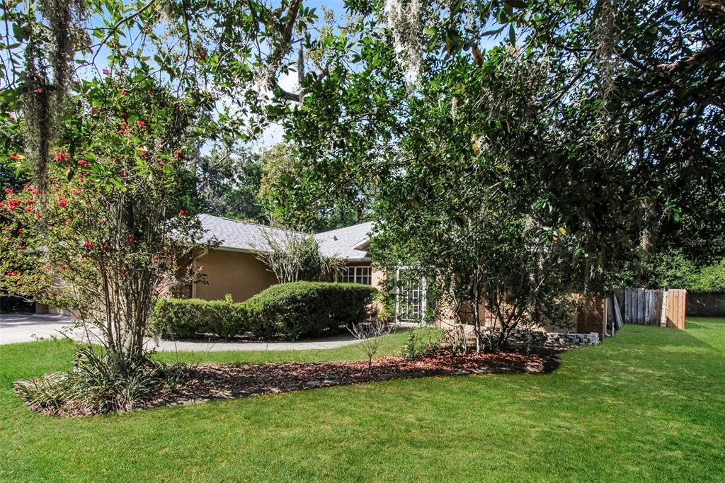 A single-story house with a tan exterior is partially obscured by trees and landscaping — 6410 JAMAICA ROAD, SPRING HILL, FL