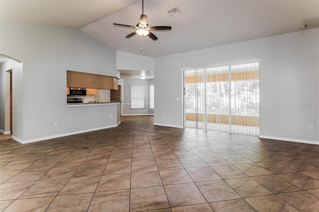 A living room with tile flooring, a ceiling fan, and sliding glass doors to a patio — 6410 JAMAICA ROAD, SPRING HILL, FL