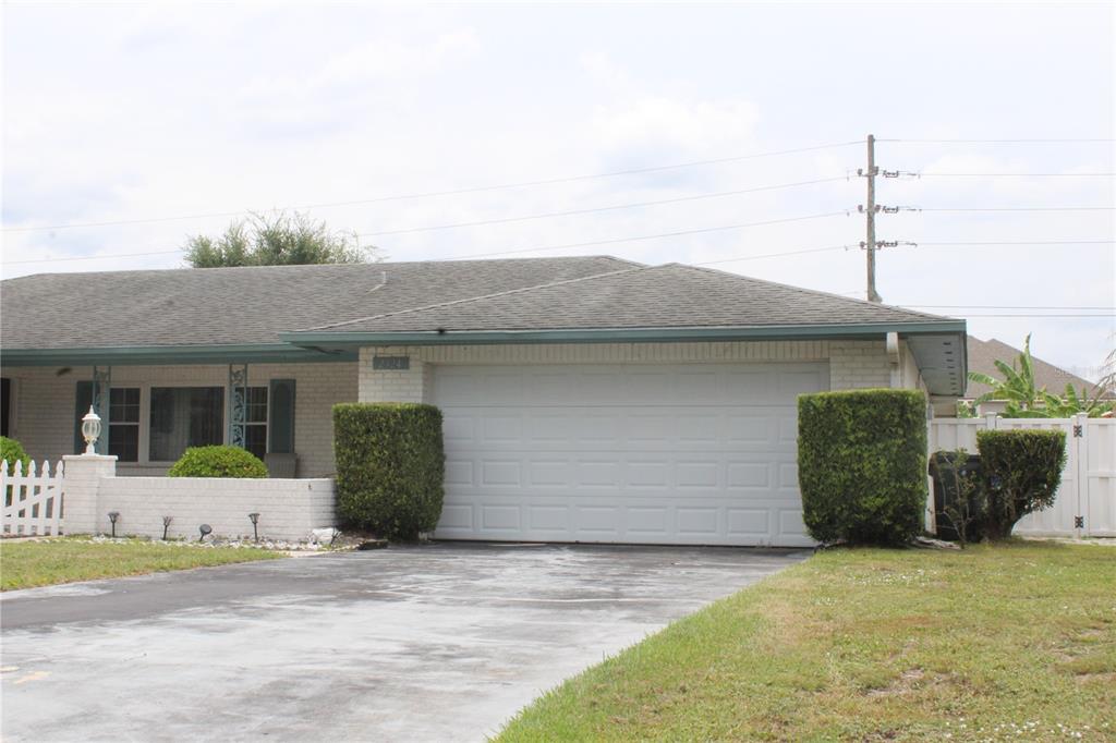 A single-story house with a white brick exterior, a two-car garage, and a paved driveway — 2324 HALEY COURT, KISSIMMEE, FL