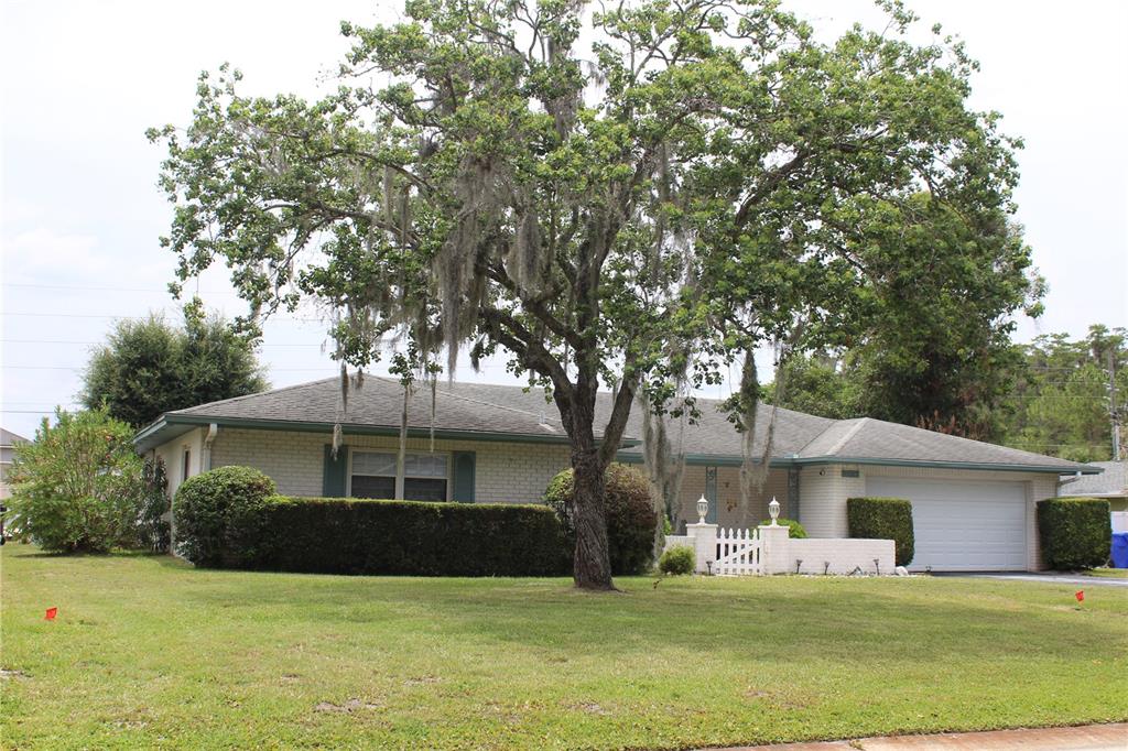 A single-story brick house with a two-car garage and a large tree in the front yard — 2324 HALEY COURT, KISSIMMEE, FL