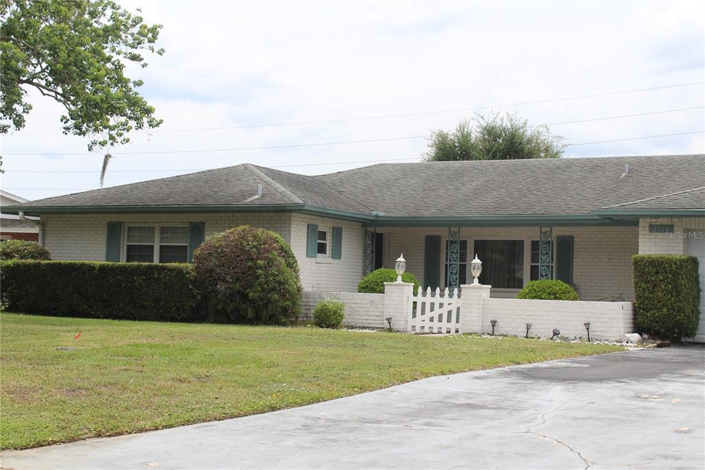 A single-story brick house with a low-pitched roof, a white picket gate, and landscaping — 2324 HALEY COURT, KISSIMMEE, FL