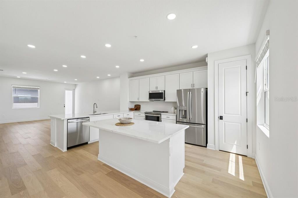 A modern kitchen features white cabinets, stainless steel appliances, and a central island — 17712 BROADLEAF LOOP, VENICE, FL