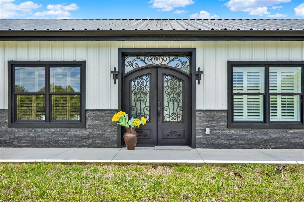 The exterior of a house features white vertical siding, stone veneer, and a double door — 34370 RICHARDSON BOULEVARD, WEBSTER, FL