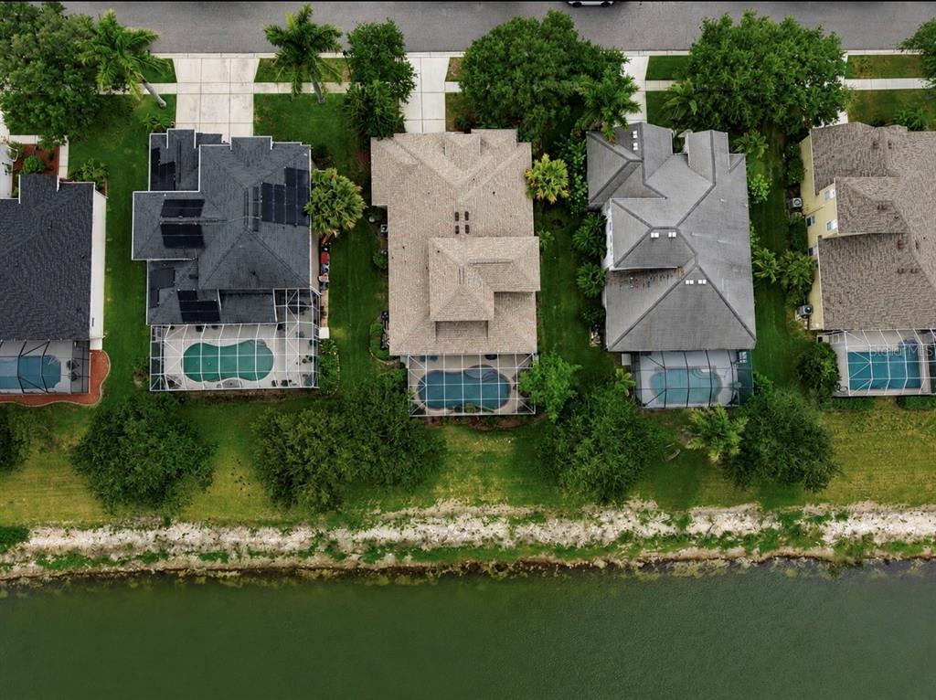 An aerial view shows four suburban houses with swimming pools along a waterfront — 827 SEMINOLE SKY DRIVE, RUSKIN, FL