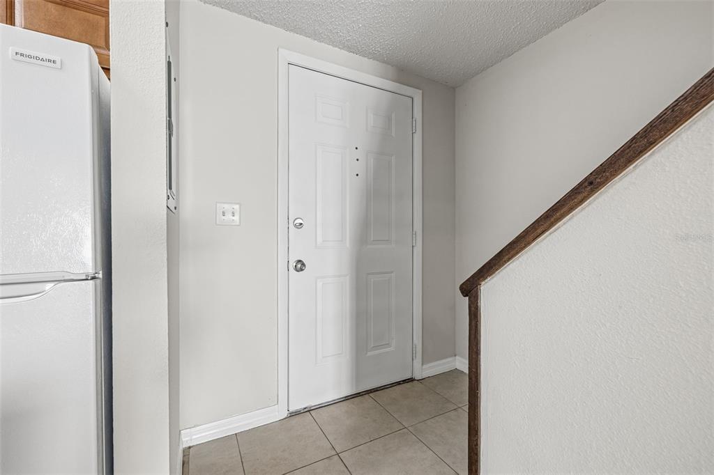 An entryway features a white door, tiled flooring, and a refrigerator to the left — 11906 CYPRESS HILL CIRCLE, TAMPA, FL