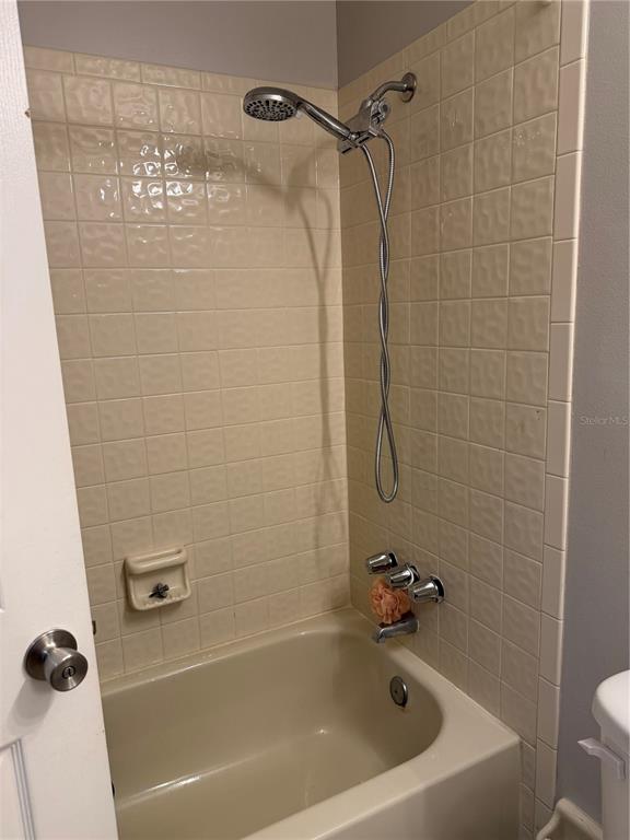 A bathroom features a beige bathtub with a handheld showerhead and tiled walls — 615 RICHLAND COURT UNIT 69, ALTAMONTE SPRINGS, FL
