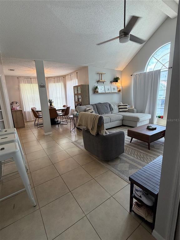 An open-concept living and dining area features tile flooring, a vaulted ceiling, and a sectional — 615 RICHLAND COURT UNIT 69, ALTAMONTE SPRINGS, FL
