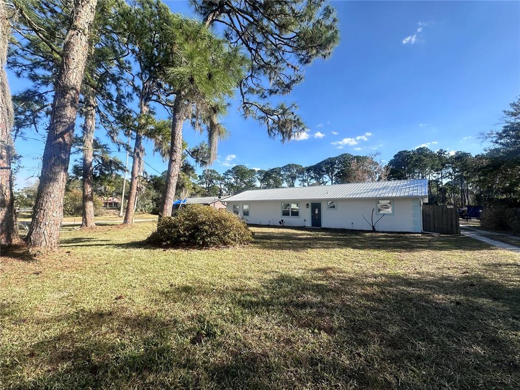 A white single-story house with a metal roof sits on a large, grassy lot — 200 28TH STREET, EDGEWATER, FL