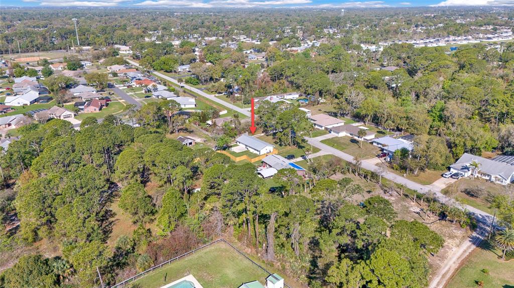 An aerial view shows a single-story house with a fenced yard surrounded by dense trees — 200 28TH STREET, EDGEWATER, FL