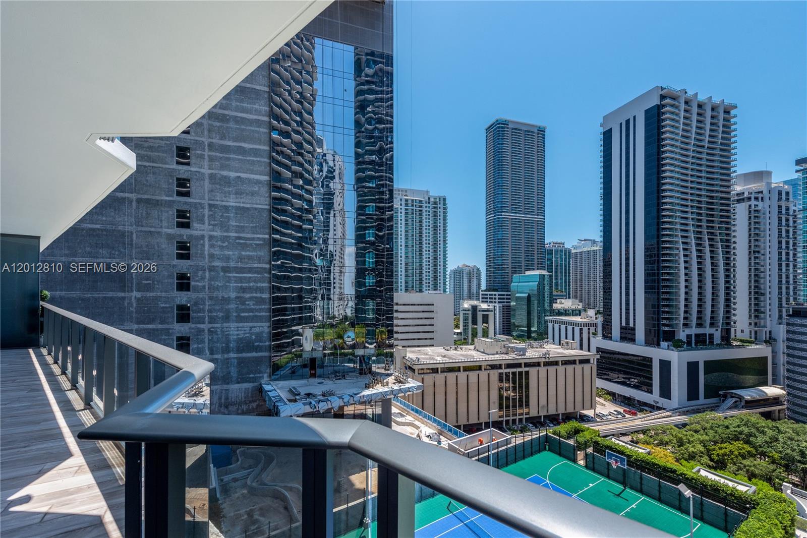 A balcony overlooks a city skyline with high-rise buildings and a tennis court below — 801 S Miami Ave # 1602, Miami FL 33130, MIAMI, FL