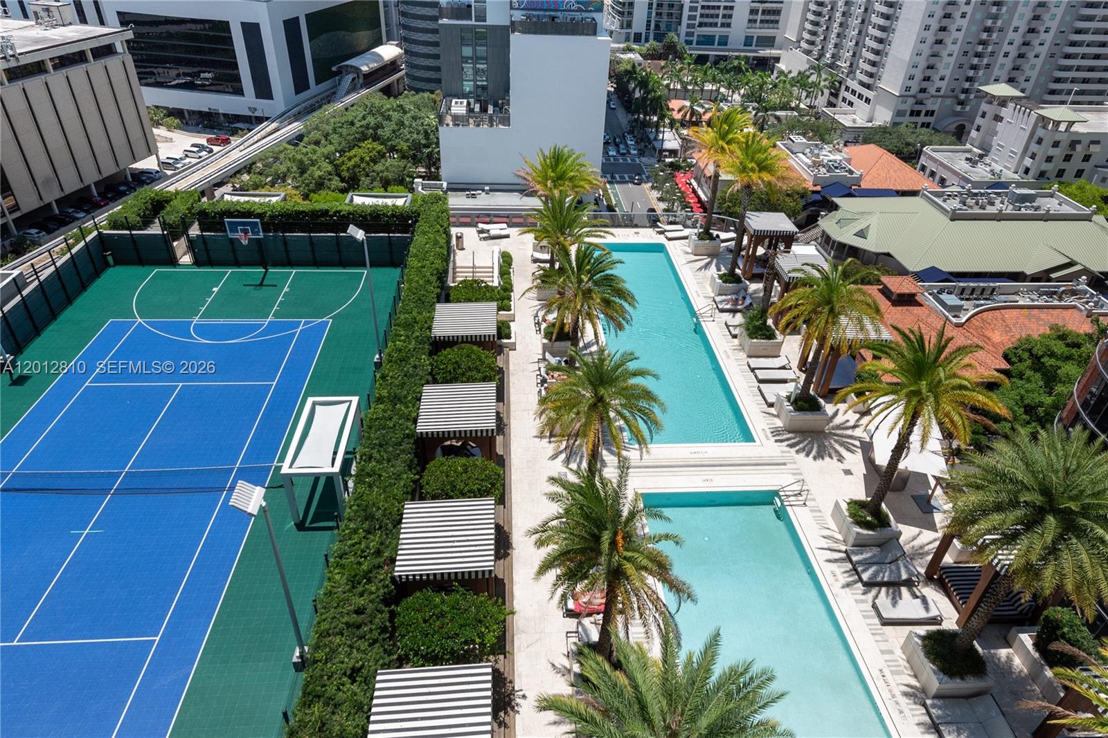An aerial view shows a rooftop amenity deck featuring a sports court and two pools — 801 S Miami Ave # 1602, Miami FL 33130, MIAMI, FL