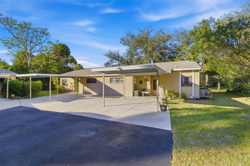 A single-story house with a large concrete carport and an asphalt driveway — 5023 VILLAGE GARDENS DRIVE UNIT 29, SARASOTA, FL
