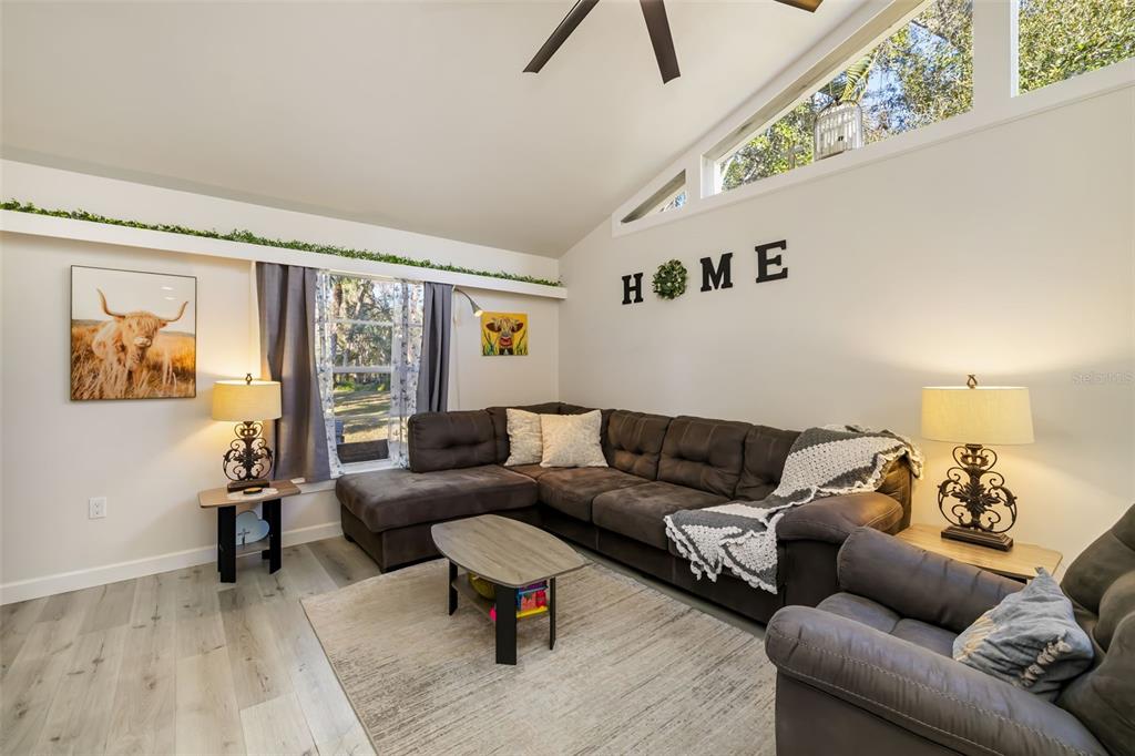 A living room features a brown sectional sofa, a coffee table, and a vaulted ceiling — 5023 VILLAGE GARDENS DRIVE UNIT 29, SARASOTA, FL