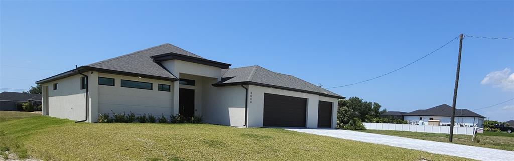 A single-story house with a white stucco exterior, dark roof, and an attached two-car garage — 3008 NW 41ST AVENUE, CAPE CORAL, FL