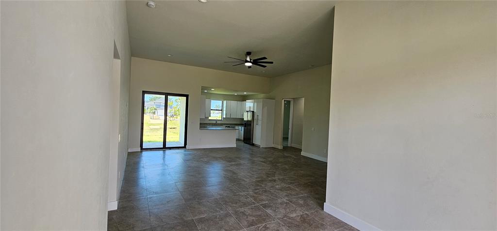 An open-concept living area features tile flooring, a ceiling fan, and a kitchen beyond — 3008 NW 41ST AVENUE, CAPE CORAL, FL