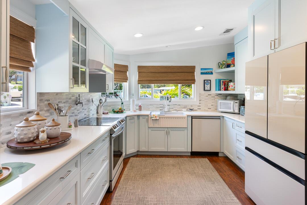 A bright kitchen features light blue cabinets, white countertops, a farmhouse sink, and wood flooring — 400 N Highway A1a # 88, Jupiter FL 33477, JUPITER, FL