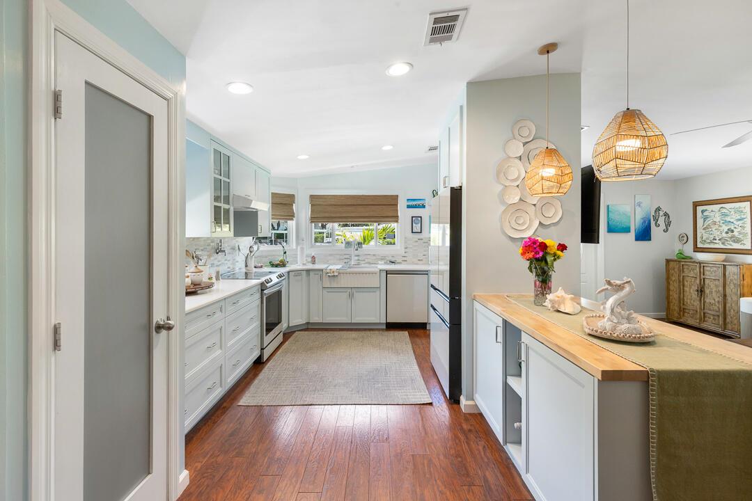 A kitchen features light blue cabinets, a wooden countertop, and a rug on wood flooring — 400 N Highway A1a # 88, Jupiter FL 33477, JUPITER, FL