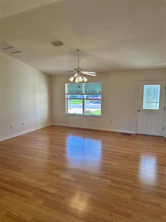 A living room with hardwood floors, a ceiling fan, and a front door — 9230 SE 179TH WESLEY STREET, THE VILLAGES, FL