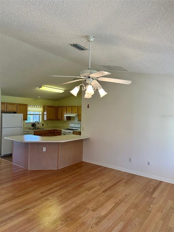 A kitchen with wood cabinets and a breakfast bar opens to a living area — 9230 SE 179TH WESLEY STREET, THE VILLAGES, FL
