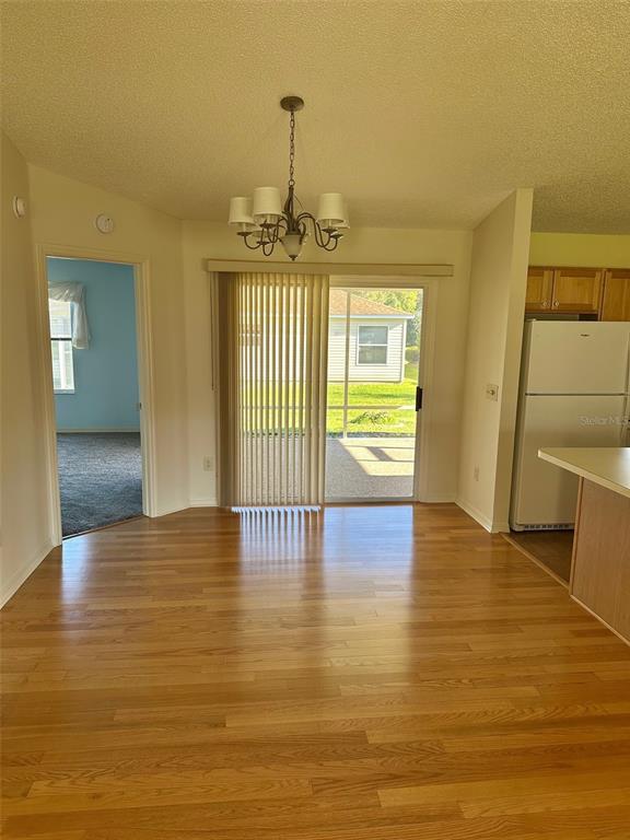 A dining area features hardwood floors, a chandelier, and sliding glass doors leading to a patio — 9230 SE 179TH WESLEY STREET, THE VILLAGES, FL
