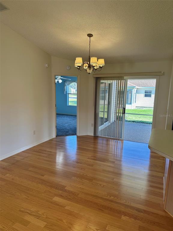 A dining area with hardwood floors, a chandelier, and a sliding glass door to a patio — 9230 SE 179TH WESLEY STREET, THE VILLAGES, FL