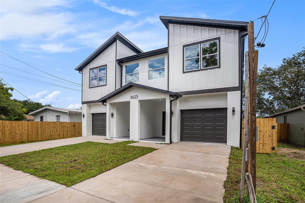 A modern two-story duplex with white siding, dark trim, and two attached garages — 3612 TEMPLE STREET, TAMPA, FL