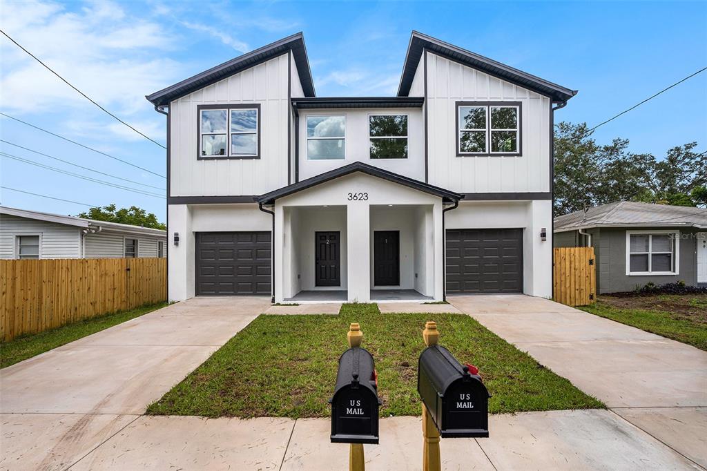 A two-story duplex with white vertical siding, dark trim, two garages, and two mailboxes — 3612 TEMPLE STREET, TAMPA, FL