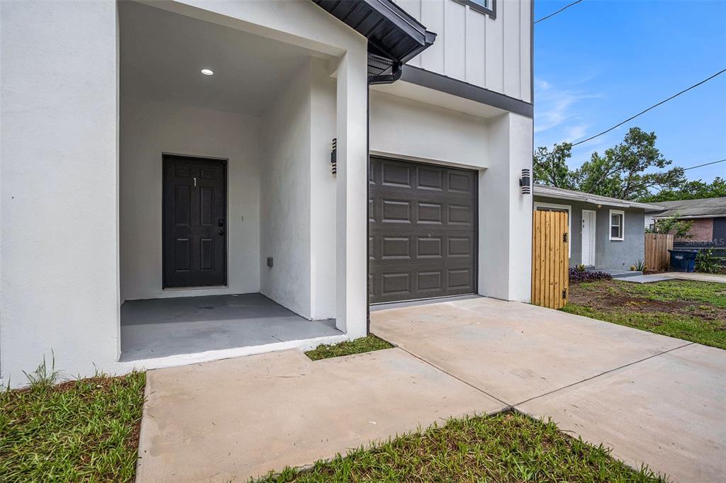 A modern two-story home exterior features a covered entryway, a dark garage door, and concrete driveway — 3612 TEMPLE STREET, TAMPA, FL