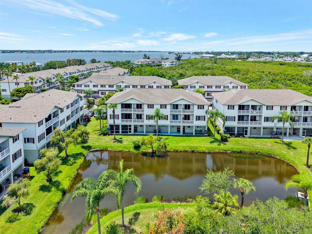 An aerial view shows multi-story apartment buildings surrounding a pond with palm trees and landscaping — 1014 34TH DRIVE W, PALMETTO, FL