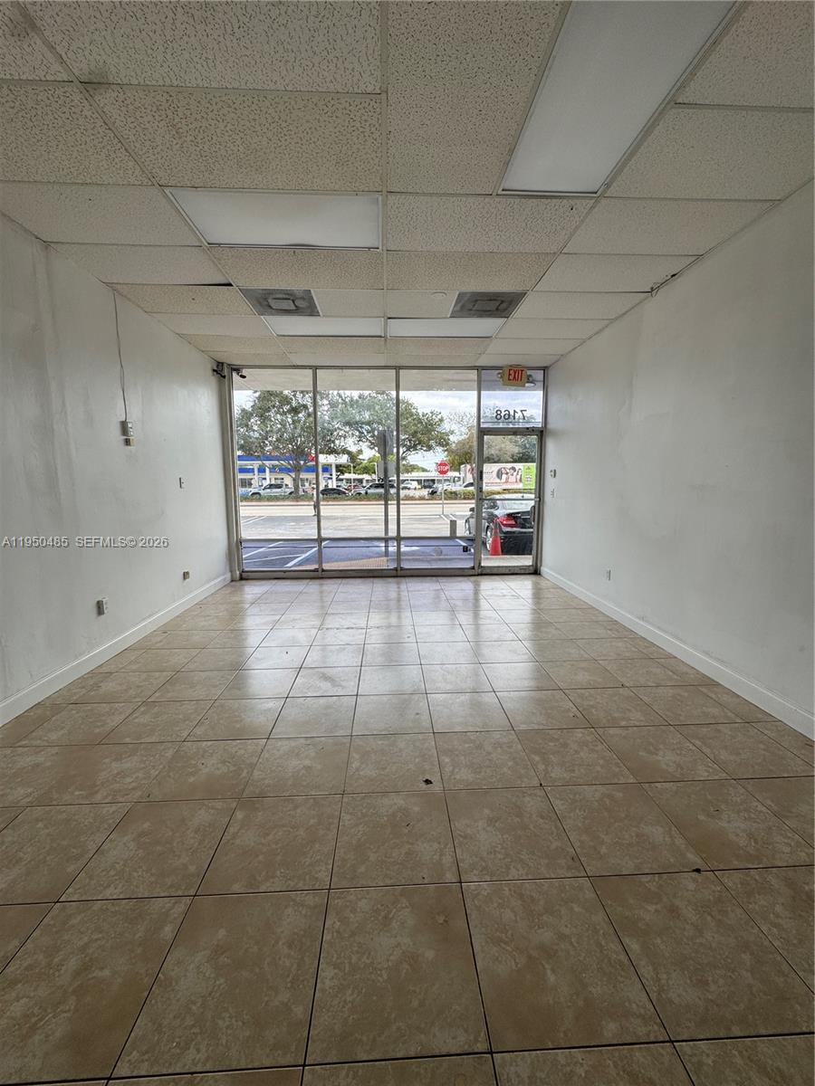 An empty commercial space features beige tile flooring, white walls, and a glass storefront — 7150 Pembroke Rd # 7168, Miramar FL 33023, MIRAMAR, FL
