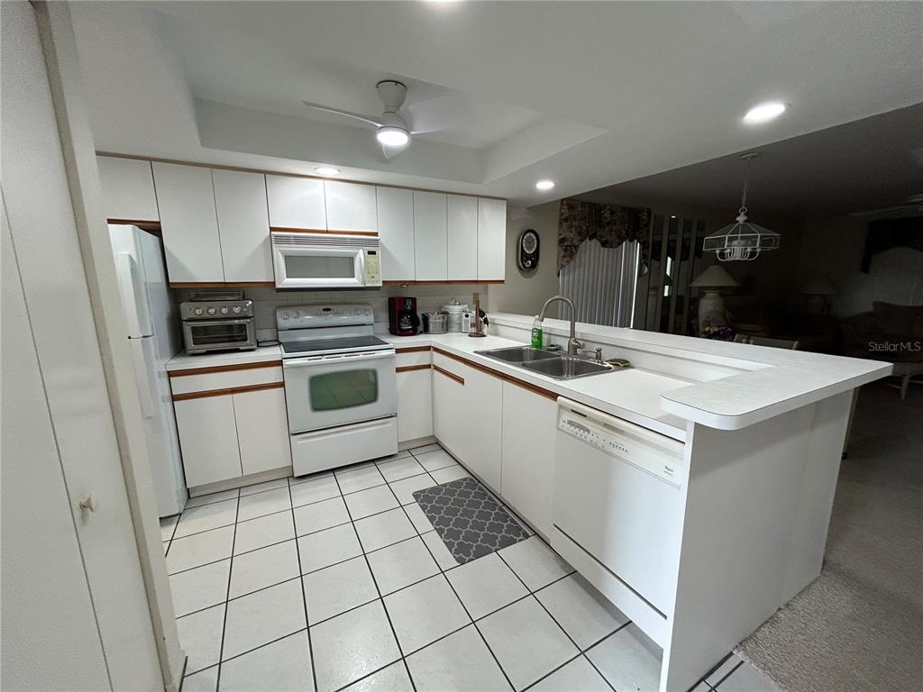 A kitchen features white cabinetry, white appliances, a tiled floor, and a breakfast bar — 6800 PLACIDA ROAD UNIT 162, ENGLEWOOD, FL