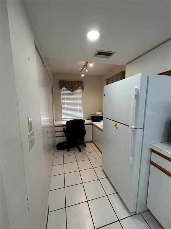 A narrow kitchen area features white cabinets, a white refrigerator, and a built-in desk space — 6800 PLACIDA ROAD UNIT 162, ENGLEWOOD, FL