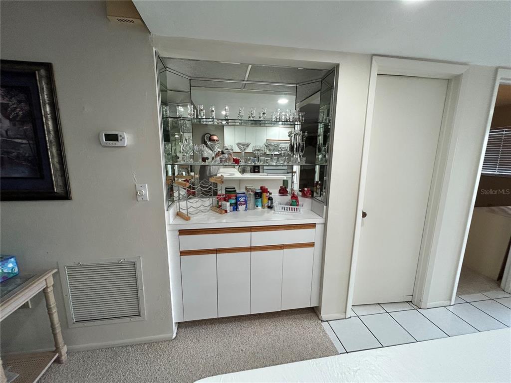 A built-in wet bar with mirrored shelving and white cabinetry sits between two doorways — 6800 PLACIDA ROAD UNIT 162, ENGLEWOOD, FL